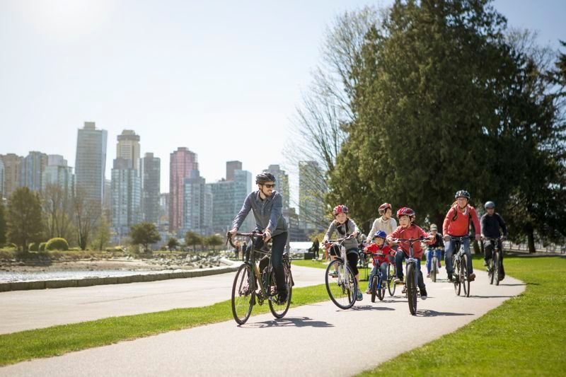 Family cycling down a trail on bikes rented from Cycle City Vancouver.