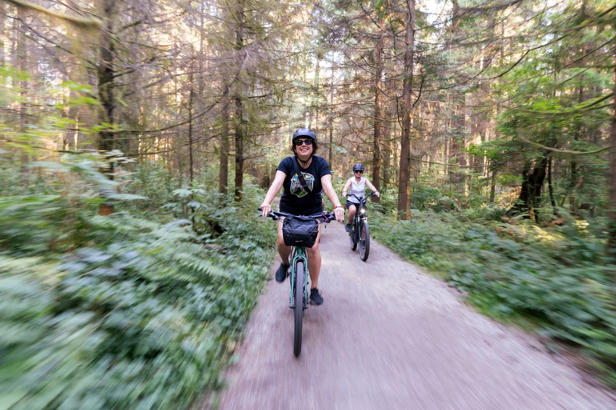 Two cyclists riding through Stanley Park on a Cycle City guided bike tour.