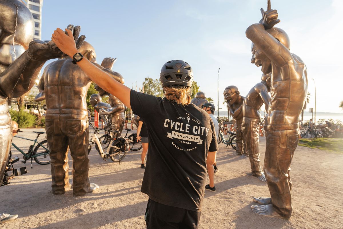 A Cycle City bike tour guide giving a thumbs up while standing amongst the A-maze-ing Laughter statues as seen on a Cycle City guided bike tour.