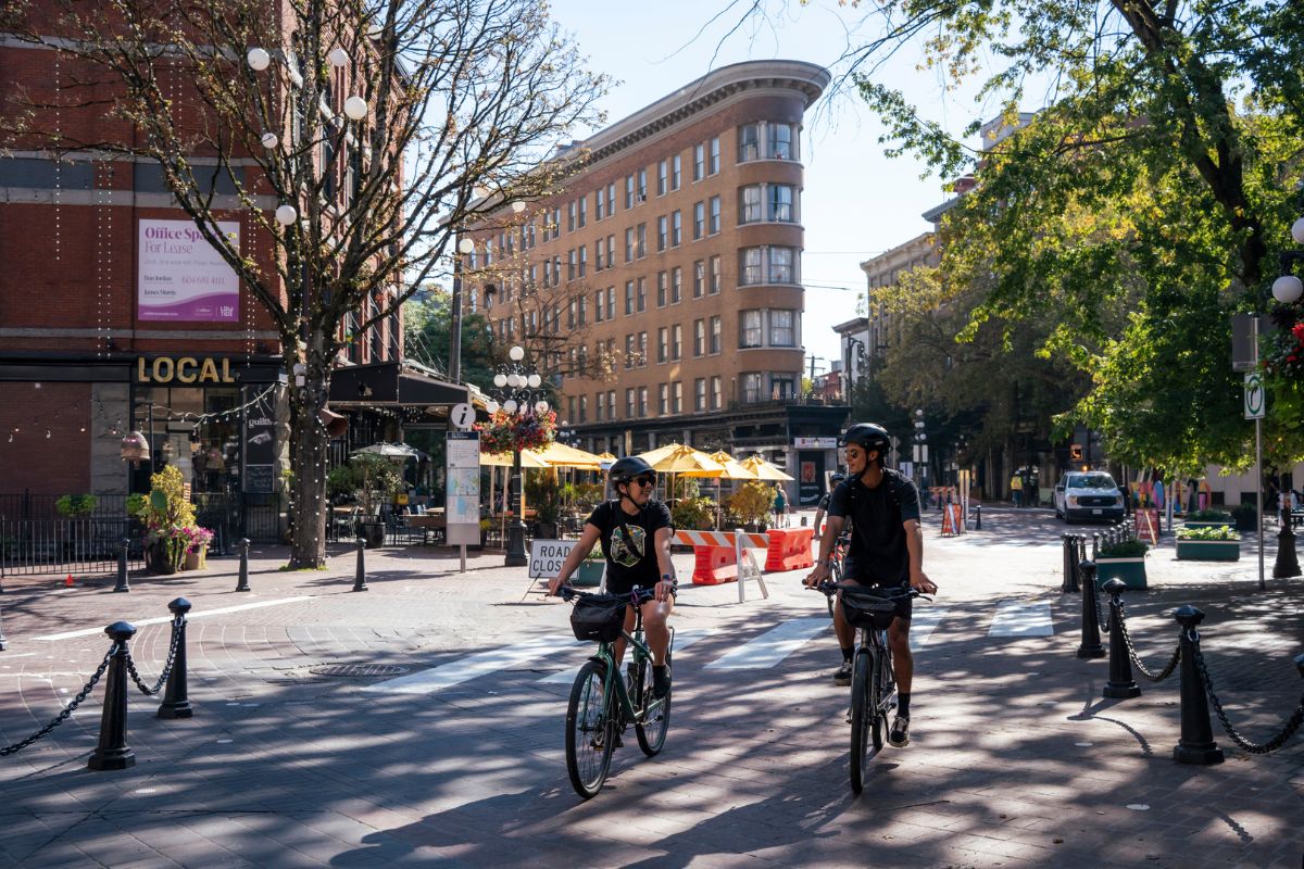 Two cyclists riding in Gastown on the Grand Bike Tour.