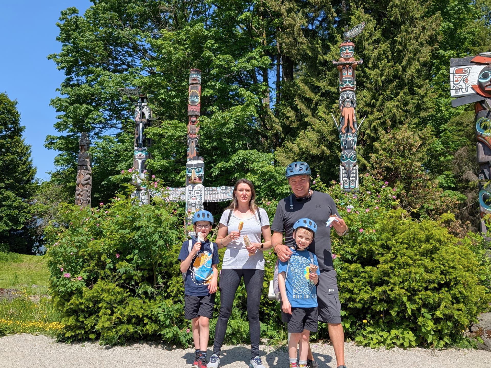 a family poses in front of the stanley park totem poles with ice cream treats