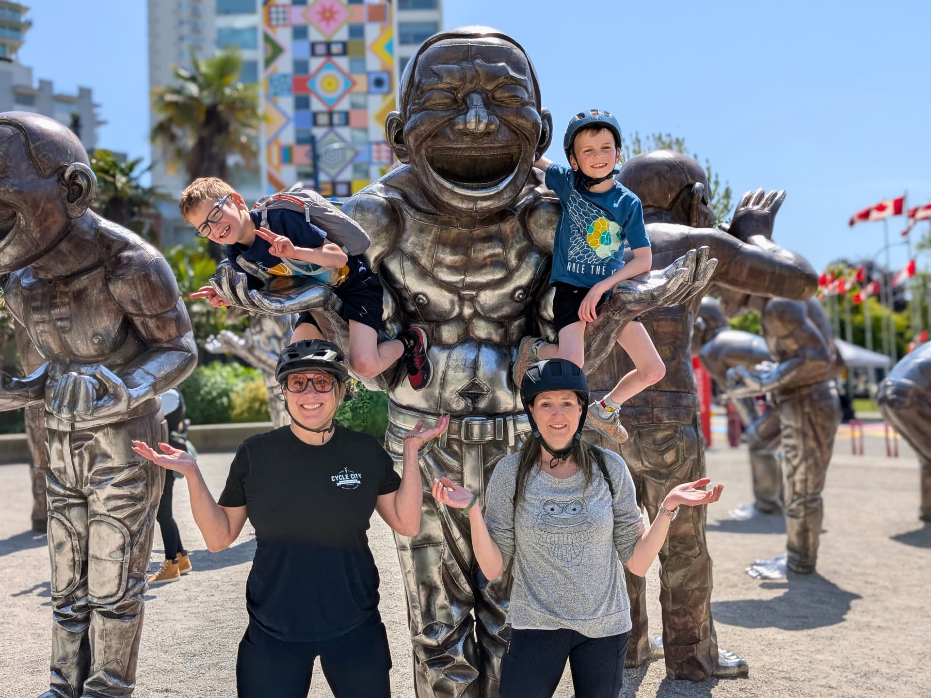 a family poses with the bike tour guide at A-Maze-Ing Laughter statues- bronze statues of the artist laughing