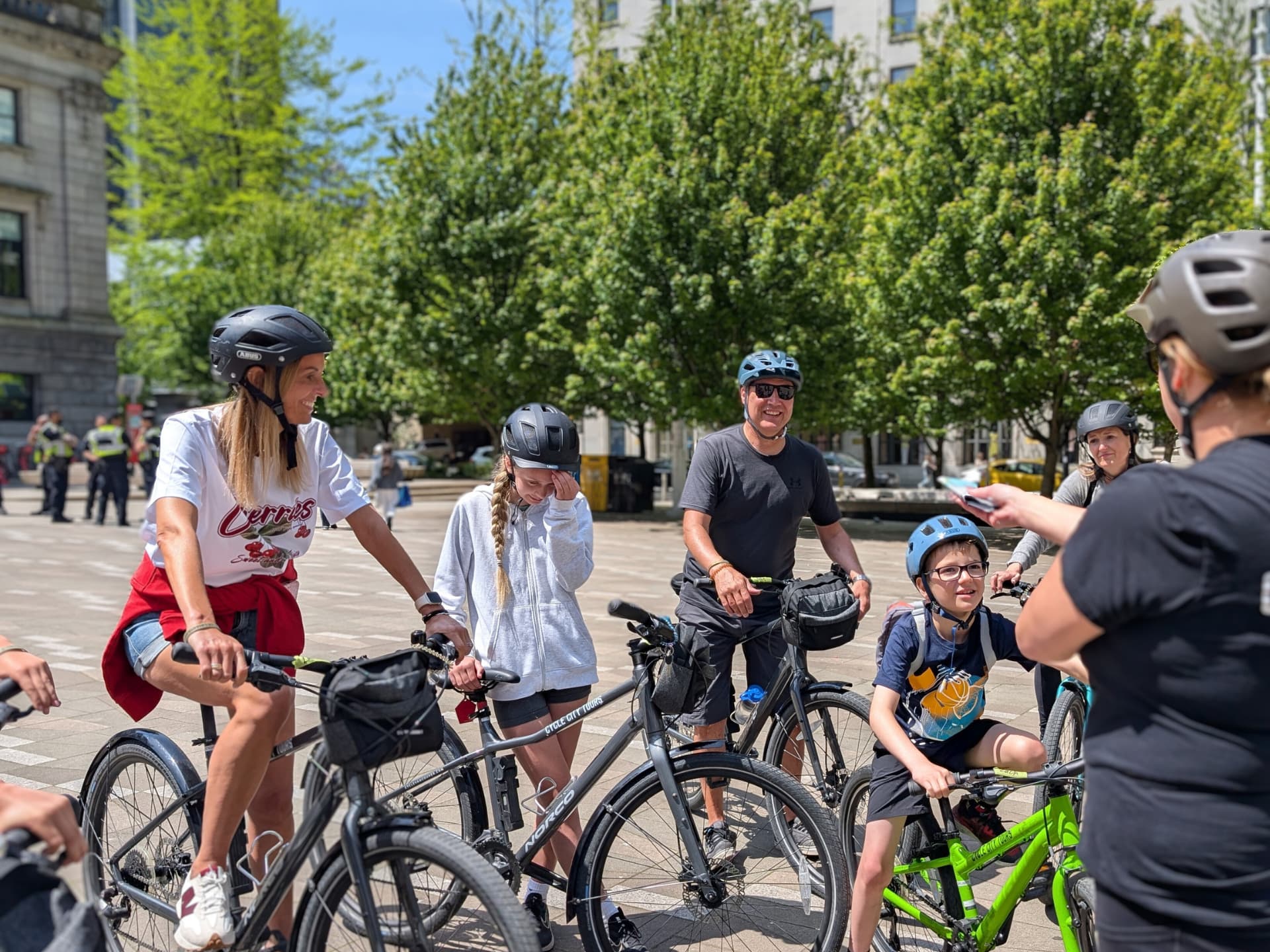 a bike tour group gathers in front of the Vancouver Art Gallery as their tour guide explains the route. Everyone is on their bikes and smiling.